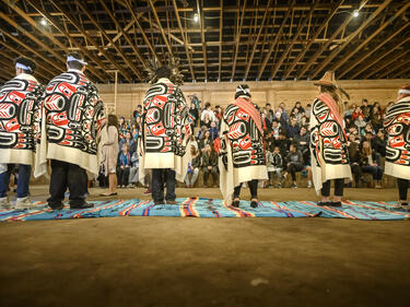 Six Aboriginal role models stand on blankets in the longhouse
