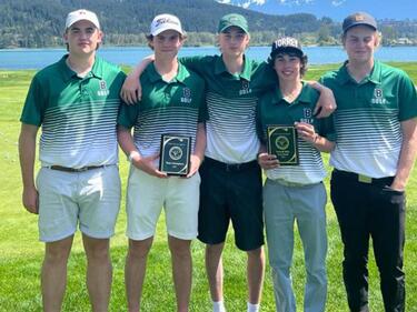 Five male golfers pose with two plaque trophies for wining tournament