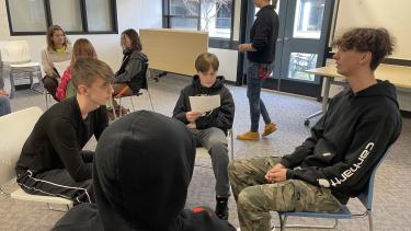 Group of 4 male students sitting in chairs in a circle