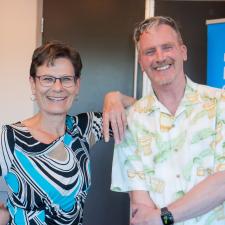 Female retiree stands with male retiree, smiling for posed photo